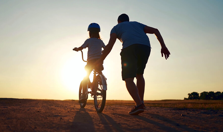 A father teaching his daughter to ride a bike